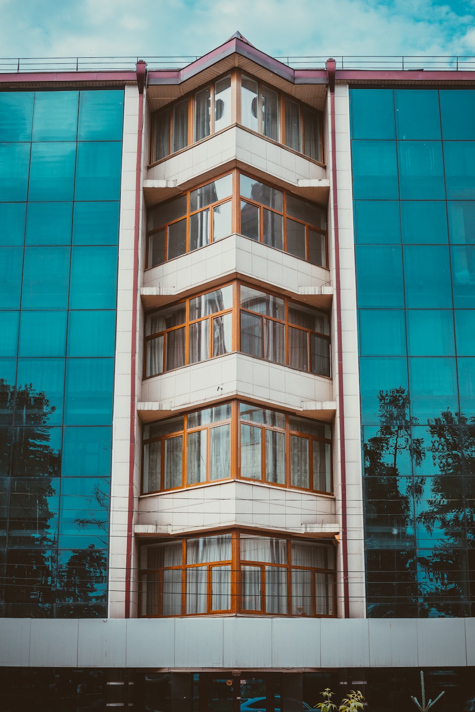 Edificio moderno con ventanas de marco de madera y paneles de vidrio azul.